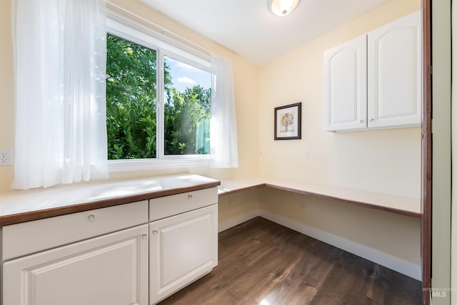 unfurnished office featuring dark wood-style flooring and baseboards