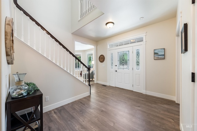 entrance foyer with dark wood-type flooring, visible vents, stairway, and baseboards