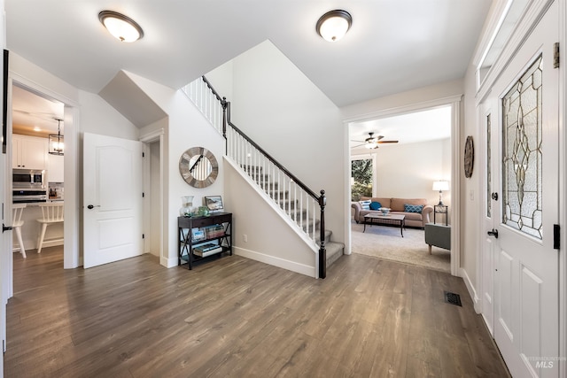 foyer featuring dark wood-type flooring, stairway, visible vents, and baseboards