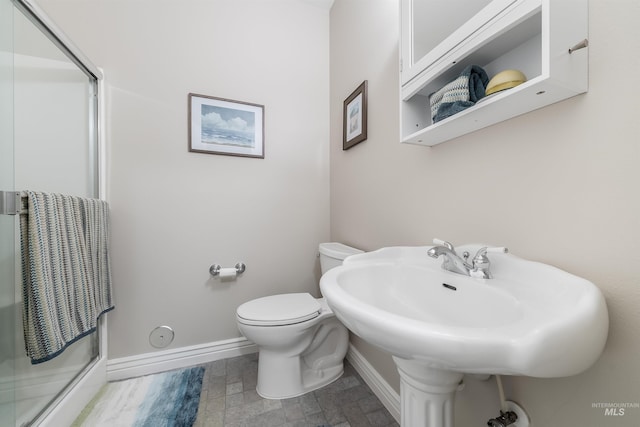 full bathroom featuring a stall shower, a sink, toilet, and baseboards