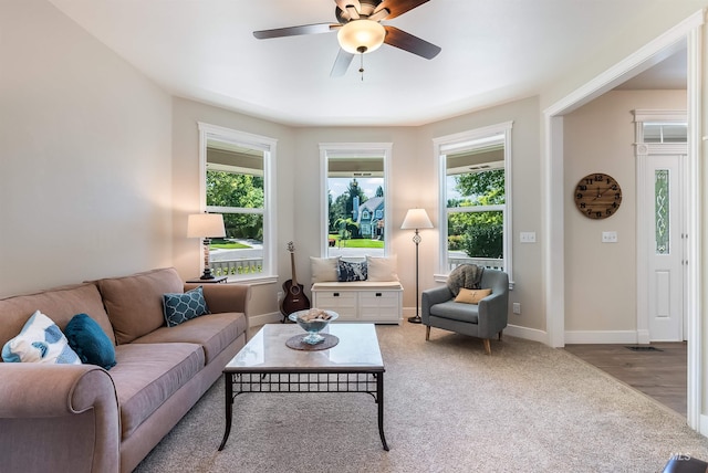 living room featuring ceiling fan, light carpet, a wealth of natural light, and baseboards