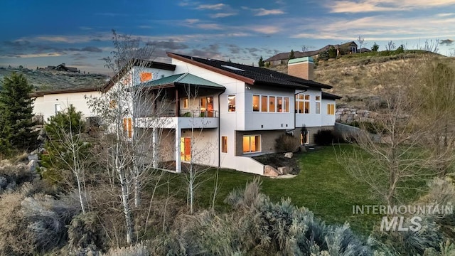 4336 N Star Vista Ln, Eagle, ID 83616 - rear view of house featuring a chimney, a balcony, a lawn, and stucco siding
