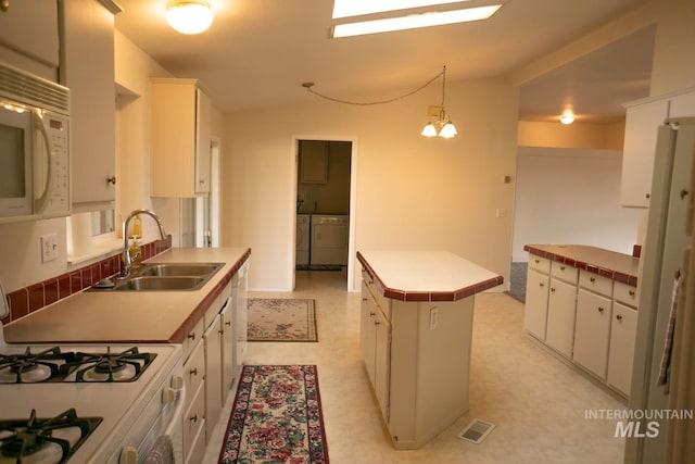 kitchen with a kitchen island, hanging light fixtures, light tile patterned floors, sink, and white appliances