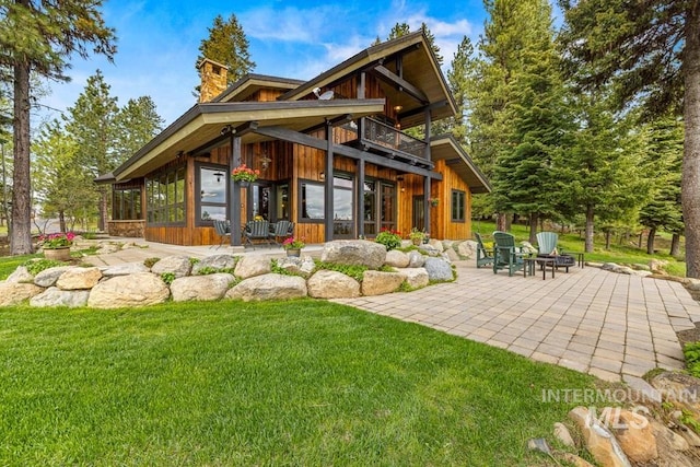 1418 Club Hill Blvd, Mccall, ID 83638 - rear view of house featuring a chimney, a sunroom, a lawn, and a patio area