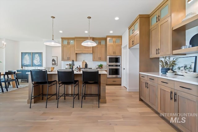 kitchen featuring recessed lighting, stainless steel appliances, hanging light fixtures, light countertops, and light wood-type flooring