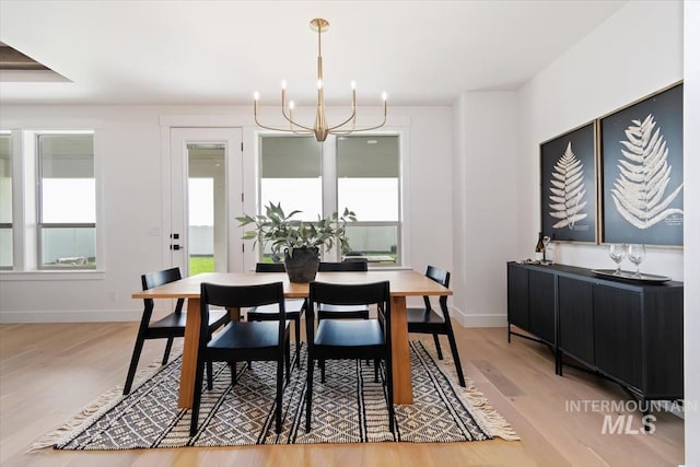 dining room with a chandelier, baseboards, and light wood-style floors