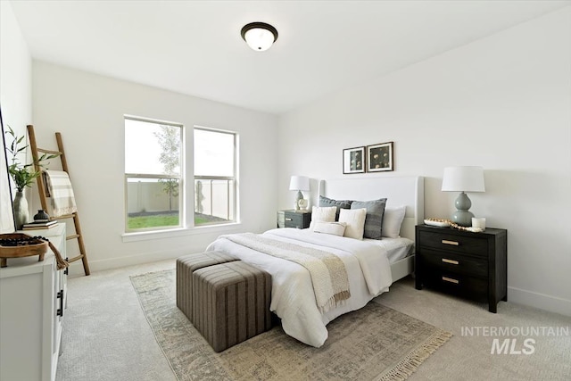 bedroom featuring light colored carpet and baseboards