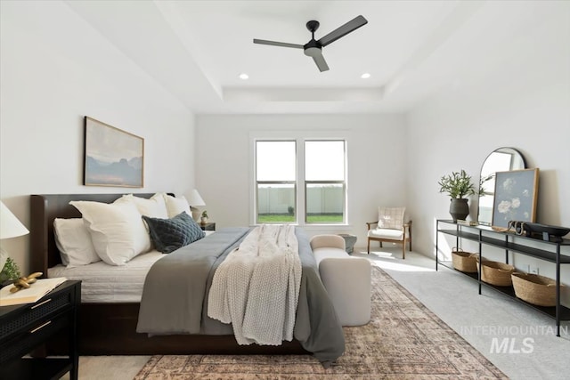 bedroom with light carpet, ceiling fan, a raised ceiling, and recessed lighting