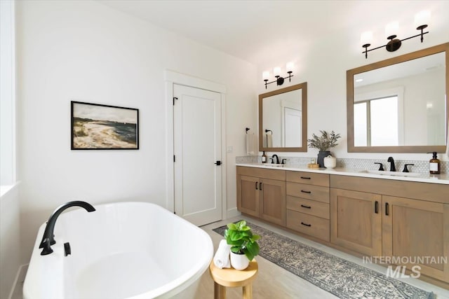 bathroom featuring double vanity, a freestanding bath, and a sink