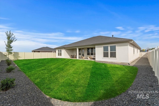 back of house with a patio area, a fenced backyard, a lawn, and stucco siding