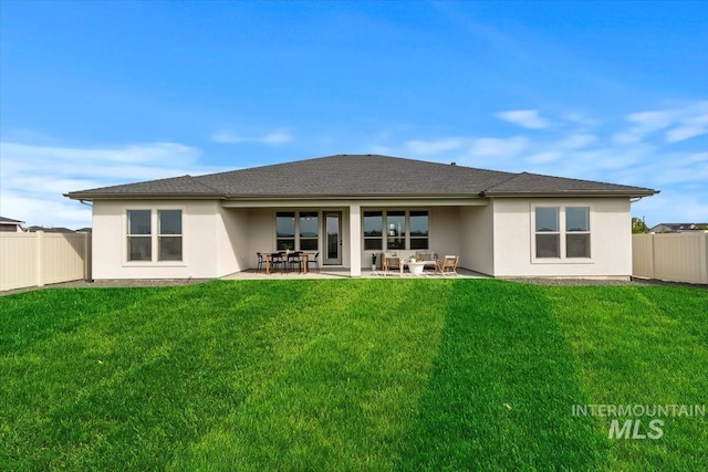 rear view of property with stucco siding, a patio area, fence, and a lawn