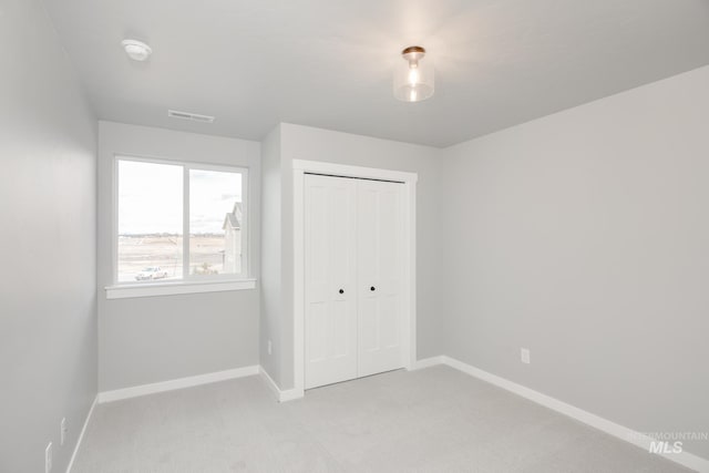 unfurnished bedroom featuring light carpet, baseboards, a closet, and visible vents