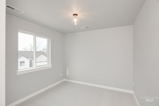 empty room featuring light colored carpet, visible vents, and baseboards