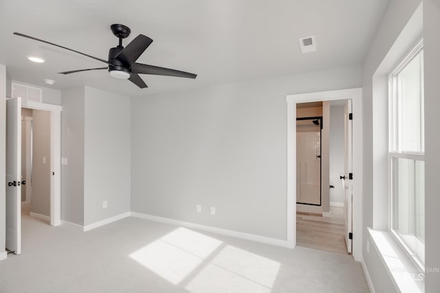 unfurnished bedroom featuring baseboards, ensuite bathroom, visible vents, and light colored carpet