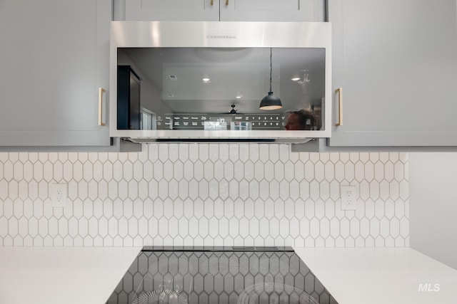 details with light countertops, stainless steel microwave, and tasteful backsplash