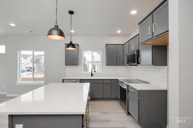 kitchen with light wood finished floors, gray cabinetry, stainless steel appliances, and tasteful backsplash