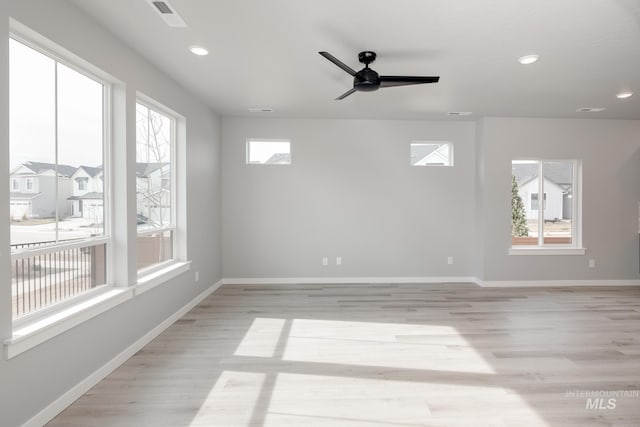 spare room with light wood-style flooring, a wealth of natural light, a ceiling fan, and visible vents