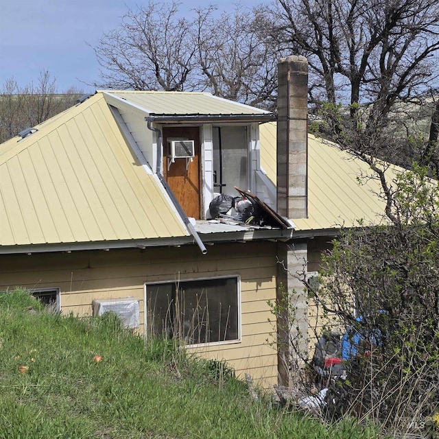 view of side of home with metal roof, a standing seam roof, and a chimney