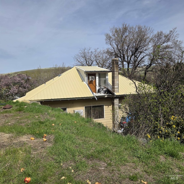 view of side of home with metal roof and a chimney