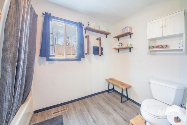 full bath featuring wood finished floors, visible vents, toilet, shower / tub combo with curtain, and baseboards
