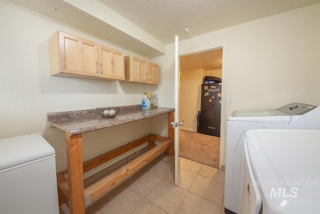 clothes washing area featuring cabinet space, a textured ceiling, light tile patterned floors, and separate washer and dryer