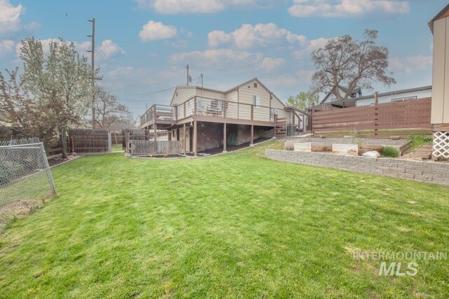 view of yard featuring a vegetable garden, a fenced backyard, and a deck