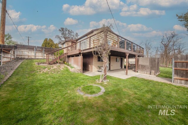 back of property featuring a lawn, fence, a patio, a wooden deck, and stairs