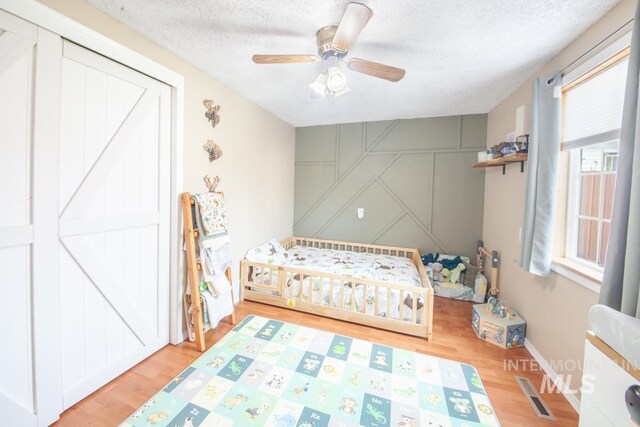 bedroom featuring visible vents, wood finished floors, a textured ceiling, and ceiling fan