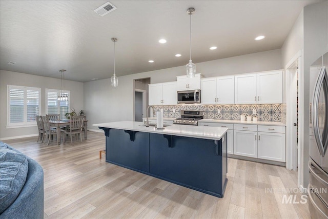 18272 N Wild Goose Ave, Nampa, ID 83687 - kitchen with appliances with stainless steel finishes, light countertops, light wood-type flooring, backsplash, and white cabinetry