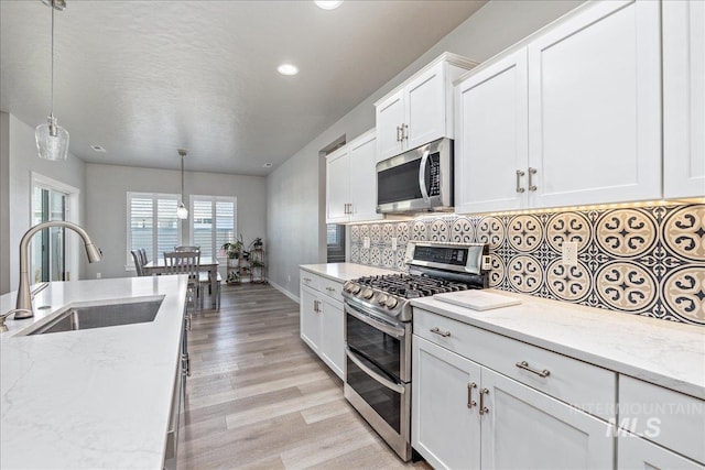 18272 N Wild Goose Ave, Nampa, ID 83687 - kitchen with stainless steel appliances, a sink, backsplash, light wood-style floors, and white cabinets