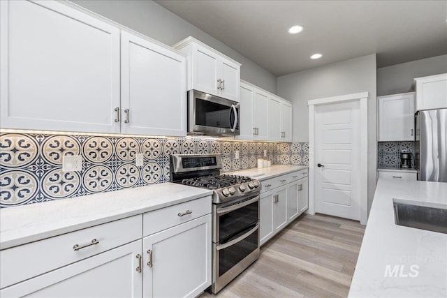 18272 N Wild Goose Ave, Nampa, ID 83687 - kitchen with stainless steel appliances, white cabinets, recessed lighting, decorative backsplash, and light wood-style floors