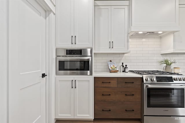 7766 W Daybreak Run Ct, Meridian, ID 83646 - kitchen with stainless steel gas range oven, white cabinetry, light countertops, decorative backsplash, and custom range hood