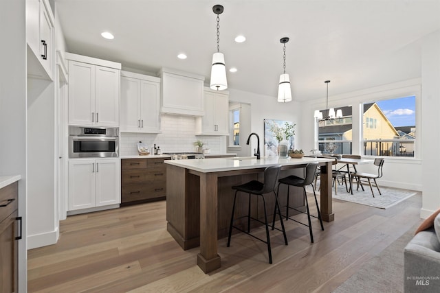 7766 W Daybreak Run Ct, Meridian, ID 83646 - kitchen with stainless steel oven, tasteful backsplash, light wood finished floors, white cabinets, and recessed lighting