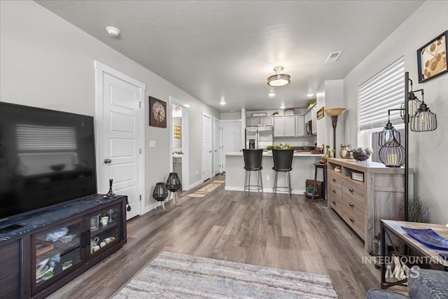 941 S Wavetrain Ave, Boise, ID 83709 - kitchen with stainless steel refrigerator with ice dispenser, wood finished floors, light countertops, a breakfast bar area, and a peninsula