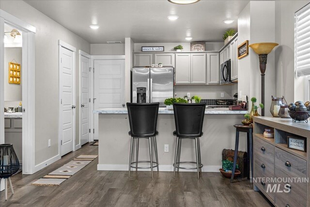 941 S Wavetrain Ave, Boise, ID 83709 - kitchen with stainless steel refrigerator with ice dispenser, a peninsula, dark wood-type flooring, a kitchen bar, and black microwave