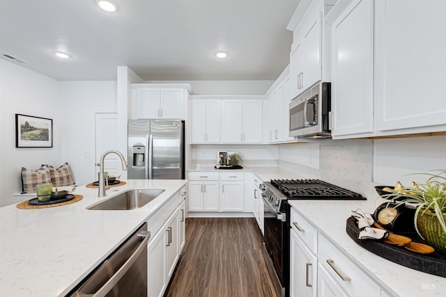 kitchen featuring stainless steel appliances, white cabinetry, sink, and light stone counters