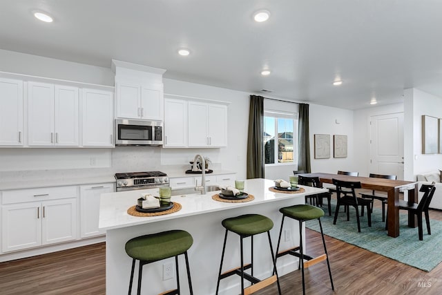 kitchen featuring white cabinetry, dark hardwood / wood-style flooring, a center island with sink, and appliances with stainless steel finishes