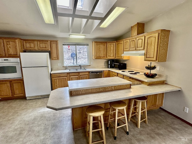 1089 Wallen Rd, Moscow, ID 83843 - kitchen featuring white appliances, a kitchen breakfast bar, under cabinet range hood, light flooring, and light countertops