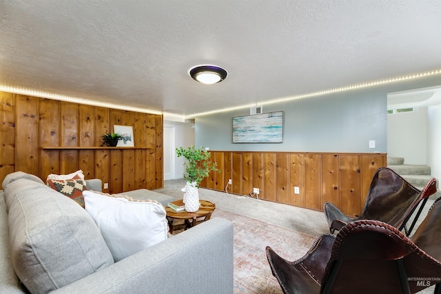 living room with wooden walls, carpet, and a textured ceiling