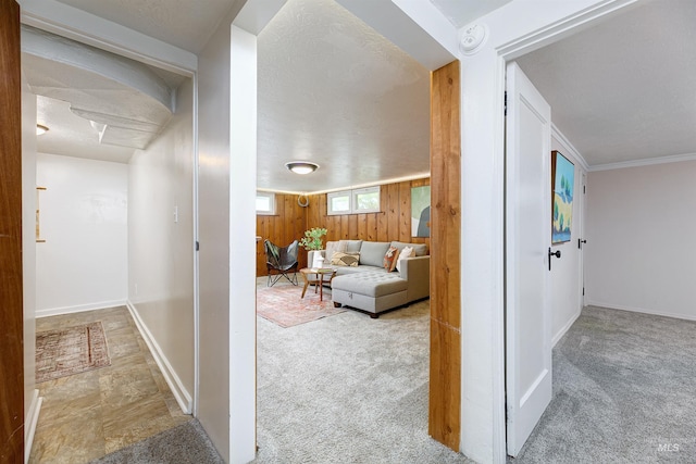 hallway featuring carpet flooring, wood walls, and ornamental molding