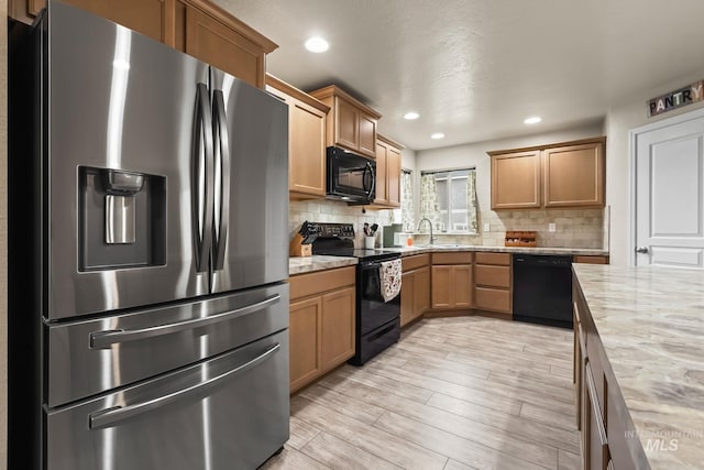 kitchen featuring tasteful backsplash, sink, light hardwood / wood-style floors, and black appliances