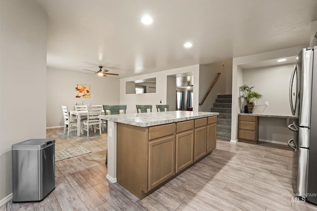 kitchen featuring ceiling fan, a kitchen island, light wood-type flooring, and stainless steel refrigerator