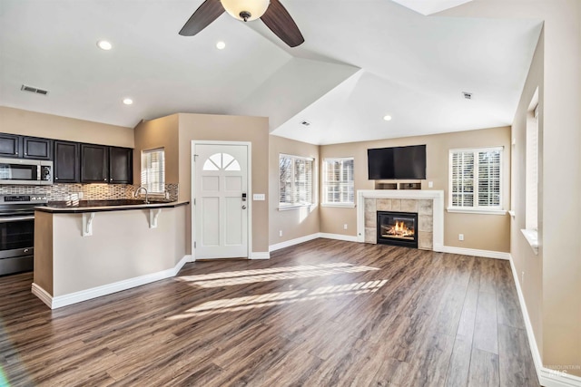 unfurnished living room with lofted ceiling, a tiled fireplace, dark hardwood / wood-style flooring, and plenty of natural light