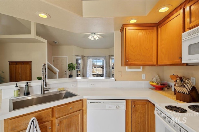 kitchen featuring brown cabinetry, white appliances, light countertops, and a sink