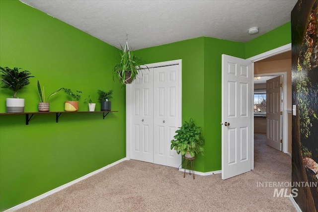 unfurnished bedroom with a textured ceiling, a closet, carpet, and baseboards