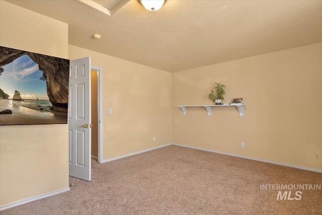 carpeted spare room with a textured ceiling and baseboards