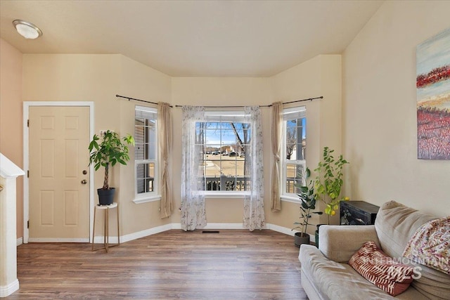 living area with wood finished floors, visible vents, and baseboards