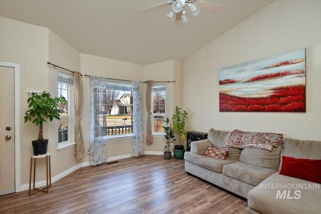 living area with a ceiling fan, visible vents, baseboards, and wood finished floors