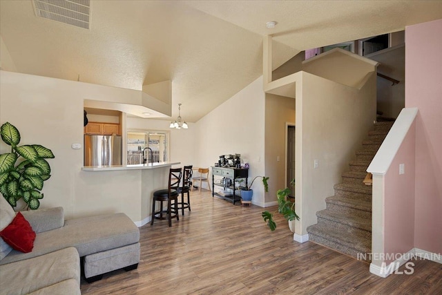 interior space featuring baseboards, visible vents, wood finished floors, stairs, and vaulted ceiling