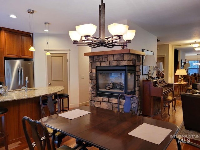 dining area with a fireplace, hardwood / wood-style flooring, and an inviting chandelier